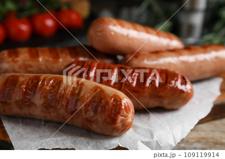 Delicious grilled sausages on wooden table, closeup 109119914