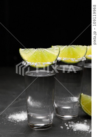 Mexican Tequila shots, lime slices and salt on black table 109119968