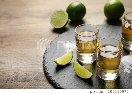 Mexican Tequila shots, lime slices and salt on wooden table Mexican Tequila shots, lime slices and salt on wooden table 109119973