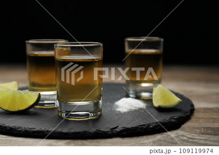 Mexican Tequila shots, lime slices and salt on wooden table Mexican Tequila shots, lime slices and salt on wooden table 109119974