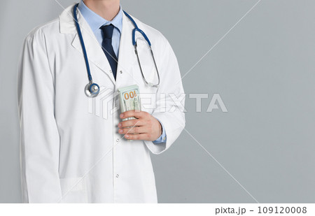 Doctor with bribe on grey background, closeup. Corruption in medicine 109120008