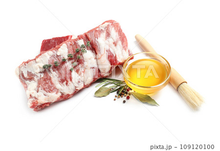 Raw ribs with herbs and oil on white background Raw ribs with herbs and oil on white background 109120100