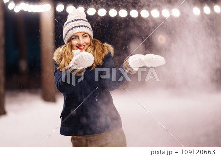 Cheerful young woman holding sparkler in hand in winter forest. Happy cute girl posing with sparkler Cheerful young woman holding sparkler in hand in winter forest. Happy cute girl posing with sparkler 109120663