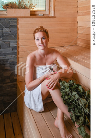 Young adult woman is steaming in the bath with a broom Young adult woman is steaming in the bath with a broom 109122529