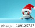 Funny chameleon in a red Santa Claus hat on a blue background. New Year or Christmas banner concept with chameleon and free space. 109125787