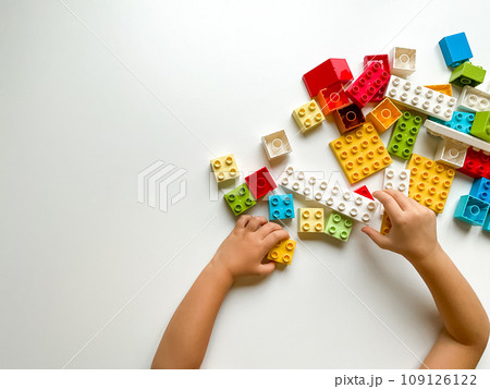 Child plays with colorful building blocks on white background. Empty space for text. View from above 109126122