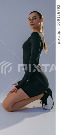 Portrait of athletic woman wearing sportswear sitting floor on studio background 109126792