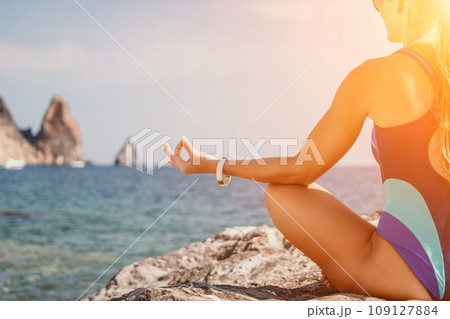 Woman sea yoga. Happy woman meditating in yoga pose on the beach, ocean and rock mountains. Motivation and inspirational fit and exercising. Healthy lifestyle outdoors in nature, fitness concept. Woman sea yoga. Happy woman meditating in yoga pose on the beach, ocean and rock mountains. Motivation and inspirational fit and exercising. Healthy lifestyle outdoors in nature, fitness concept. 109127884