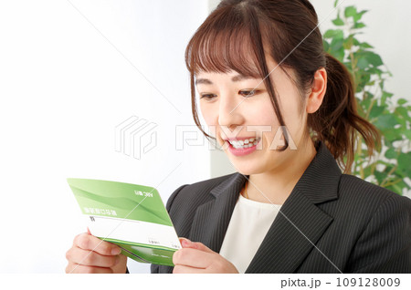 通帳をみて嬉しそうな表情をする女性 109128009