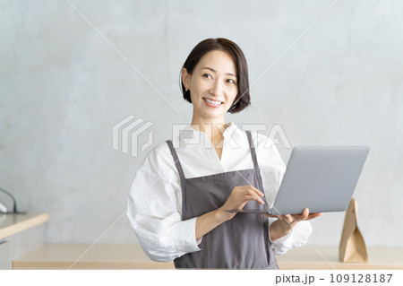 ノートパソコンを持つエプロン姿の女性 ノートパソコンを持つエプロン姿の女性 109128187