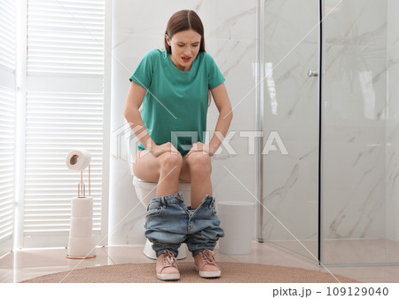 Woman suffering from hemorrhoid on toilet bowl in rest room Woman suffering from hemorrhoid on toilet bowl in rest room 109129040