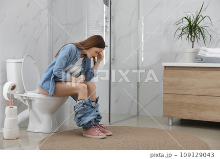 Woman suffering from hemorrhoid on toilet bowl in rest room 109129043