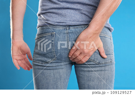 Man suffering from hemorrhoid on light blue background, closeup Man suffering from hemorrhoid on light blue background, closeup 109129527