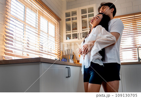 Asian man hug woman from the back and woman look like doze and happy in love and they stay in the kitchen. 109130705