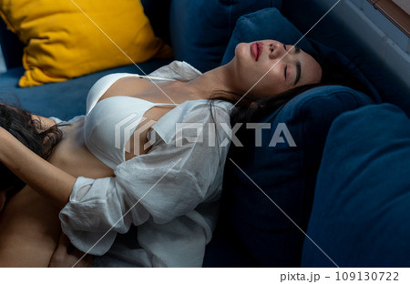 Asian woman lie down on sofa and man coax or soothe at lower body of the woman and she look happy Asian woman lie down on sofa and man coax or soothe at lower body of the woman and she look happy 109130722