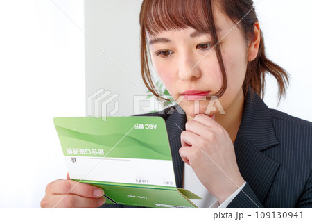 真剣な表情で通帳を見つめる若い女性 真剣な表情で通帳を見つめる若い女性 109130941