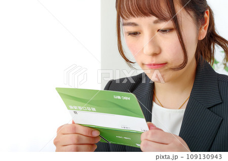 真剣な表情で通帳を見つめる若い女性 真剣な表情で通帳を見つめる若い女性 109130943