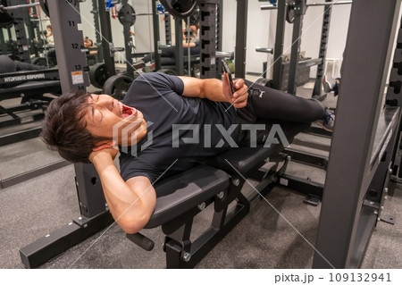 トレーニングをさぼって、あくびをしてスマホを見ている 109132941