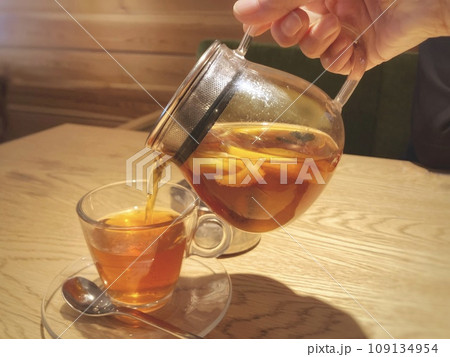 耐熱カップにフルーツティーを注ぐ手元 109134954