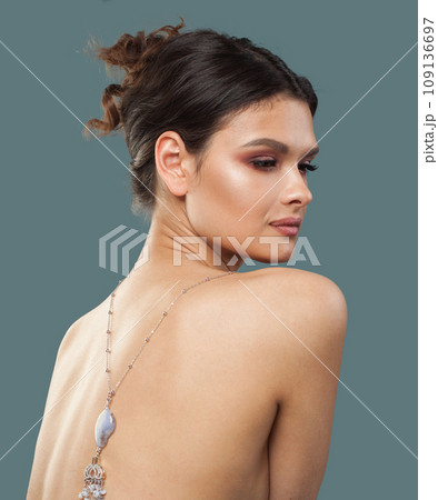 Elegant jewelry model brunette woman with healthy clear skin and dark brown hair on blue background Elegant jewelry model brunette woman with healthy clear skin and dark brown hair on blue background 109136697