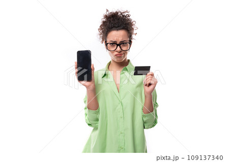 young brunette businesswoman with curly hair dressed in green shirt holding plastic credit card 109137340