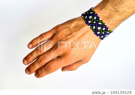 Male hand with colorful friendship bracelet handmade of thread with knots isolated on white background 109139329