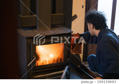 古民家で焚火ストーブを付ける人 109139693