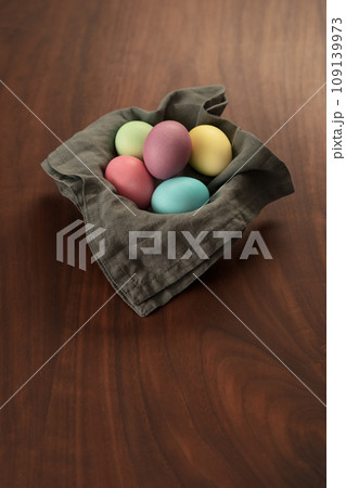 Easter eggs in a bowl with napkin on walnut wood table with copy space 109139973