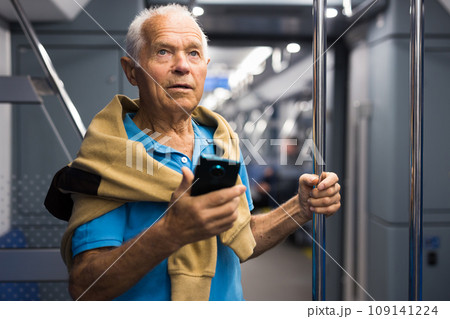 Positive elderly passenger talking on mobile phone in subway car Positive elderly passenger talking on mobile phone in subway car 109141224
