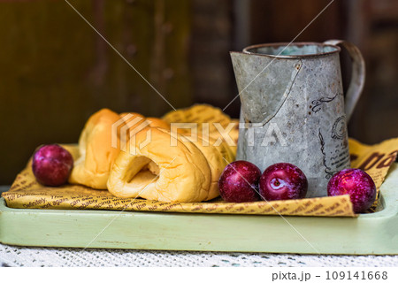 whipped cream tubes with cup and plums on wooven cloth on black background 109141668