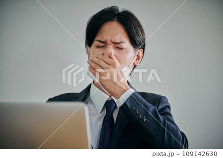 手で口を覆うマスク姿の男性会社員 109142630