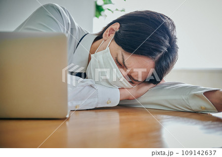 仕事疲れでうつ伏せになるYシャツ姿の男性会社員 仕事疲れでうつ伏せになるYシャツ姿の男性会社員 109142637