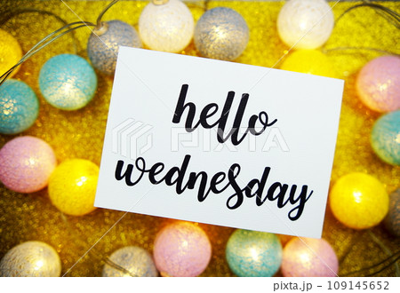 Hello Wednesday text on paper card top view on yellow bokeh background 109145652