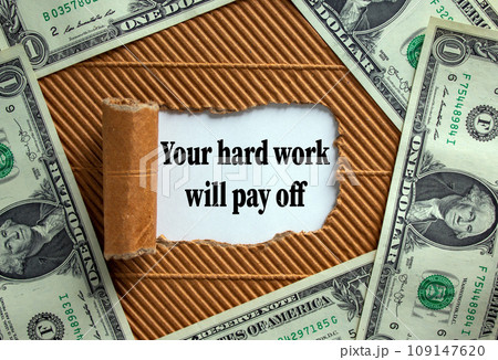 The text 'your hard work will pay off' appearing behind torn brown paper. Dollar bills. Business concept. 109147620