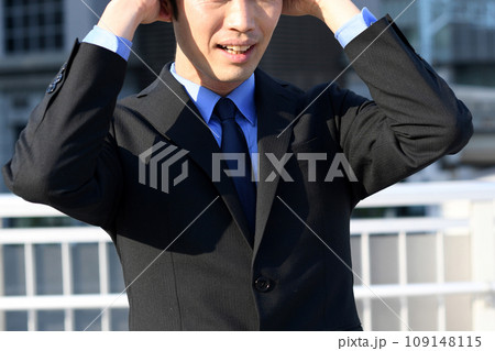 屋外で頭を抱えなが屋外で頭を抱えながら悩むスーツ姿のアジア人のら悩むスーツ姿のアジア人のビジネスマン 109148115