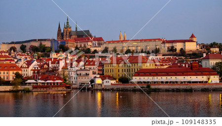 Prague Castle on a hill with surrounding buildings and river under a pinkish sky. Prague Castle on a hill with surrounding buildings and river under a pinkish sky. 109148335