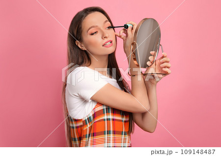 Beauty blogger applying mascara on pink background Beauty blogger applying mascara on pink background 109148487