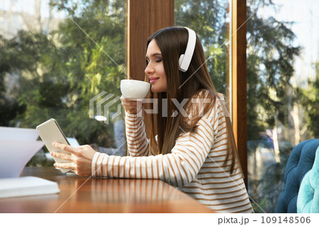Woman listening to audiobook at table in cafe 109148506