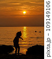 Silhouette of a little girl playing on the seashore during sunset 109149106