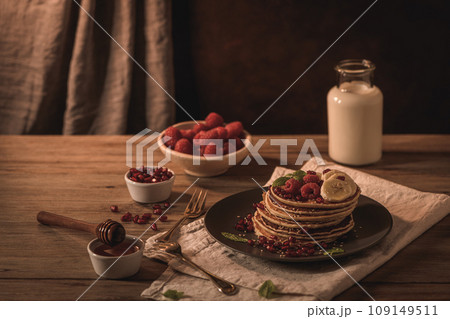 Pancakes with raspberries, banana slices, pomegranate seeds and honey Pancakes with raspberries, banana slices, pomegranate seeds and honey 109149511
