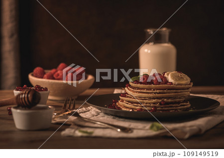 Pancakes with raspberries, banana slices, pomegranate seeds and honey 109149519