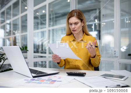 Young female accountant, financial analyst working in with documents in office, problems with accounts and report, looks worried and spreads hands. Young female accountant, financial analyst working in with documents in office, problems with accounts and report, looks worried and spreads hands. 109150008