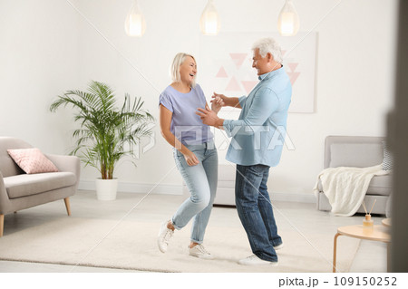 Happy mature couple dancing together in living room 109150252