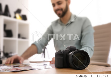 Professional photographer working at table in office, focus on camera 109150253