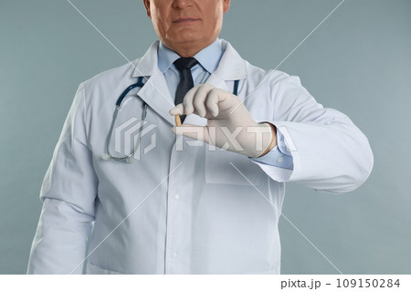 Doctor holding suppository for hemorrhoid treatment on light grey background, closeup Doctor holding suppository for hemorrhoid treatment on light grey background, closeup 109150284