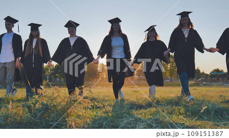 Graduate students walking through an evening meadow at sunset. Graduate students walking through an evening meadow at sunset. 109151387