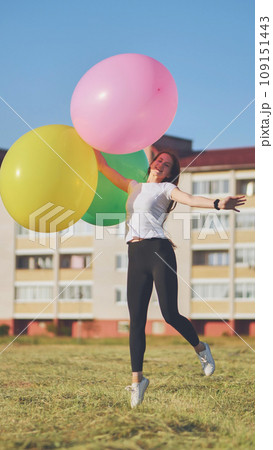 A girl happily poses with large with colorful balloons in the city. A girl happily poses with large with colorful balloons in the city. 109151443