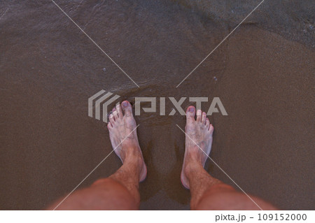 Male feet on sea sand. 109152000