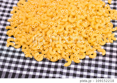 Scattered Uncooked Chifferi Rigati Pasta on Black Checkered Towel 109152218