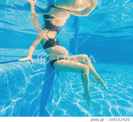 Embracing aquatic fitness, a pregnant woman demonstrates strength and serenity in underwater aerobics, creating a serene and empowering image in the pool 109152420